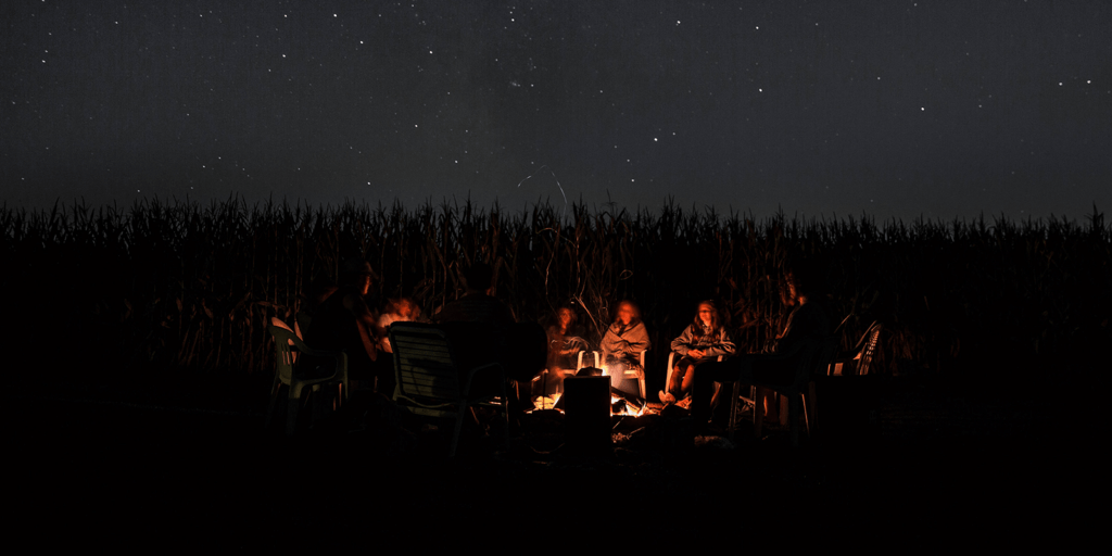 Menschen sitzen im Dunkeln am Lagerfeuer