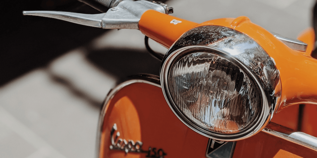 orangefarbige Vespa auf einer Straße